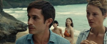 Movie still from “Old” (2021), directed by M. Night Shyamalan – A man standing next to two women on a beach; Close Up shot, Over the shoulder angle