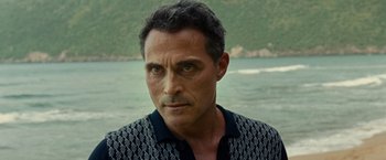 Movie still from “Old” (2021), directed by M. Night Shyamalan – A person wearing a shirt near a body of water; Close Up shot, Over the shoulder angle