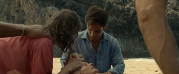 Movie still from “Old” (2021), directed by M. Night Shyamalan – A man and two women standing next to each other on a beach; Close Up shot, Over the shoulder angle