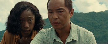 Movie still from “Old” (2021), directed by M. Night Shyamalan – A person wearing a shirt with mountains in the background; Close Up shot, Low angle