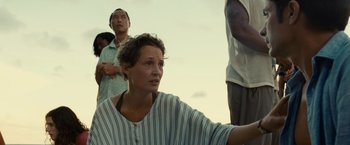 Movie still from “Old” (2021), directed by M. Night Shyamalan – A woman sitting in front of a group of people; Medium shot, Low angle