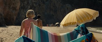 Movie still from “Old” (2021), directed by M. Night Shyamalan – A group of people standing on top of a sandy beach; Extreme Wide shot, High angle