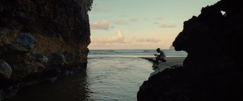Movie still from “Old” (2021), directed by M. Night Shyamalan – A man sitting on a rock near the ocean; Extreme Wide shot, Low angle