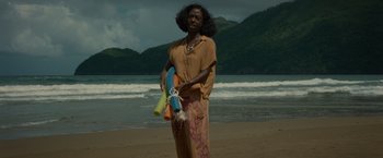 Movie still from “Old” (2021), directed by M. Night Shyamalan – A woman standing on a beach holding a bunch of balloons; Medium shot, High angle