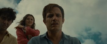 Movie still from “Old” (2021), directed by M. Night Shyamalan – A man and a woman standing next to each other in front of a cloudy sky; Close Up shot, Low angle