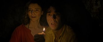 Movie still from “Old” (2021), directed by M. Night Shyamalan – A man and a woman holding a lit candle in the dark; Close Up shot, High angle