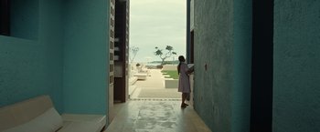 Movie still from “Old” (2021), directed by M. Night Shyamalan – A woman standing in a doorway looking out at the ocean; Extreme Wide shot, Over the shoulder angle
