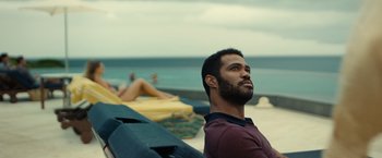 Movie still from “Old” (2021), directed by M. Night Shyamalan – A man sitting on a bench on the beach; Medium shot, Over the shoulder angle