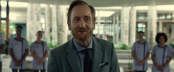 Movie still from “Old” (2021), directed by M. Night Shyamalan – A person wearing a suit and tie; Close Up shot, Over the shoulder angle