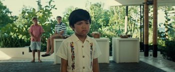 Movie still from “Old” (2021), directed by M. Night Shyamalan – A young boy wearing a white shirt and a colorful tie; Medium shot, Over the shoulder angle