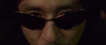 Movie still from “Oldboy” (2003), directed by Park Chan-wook – A person's face wearing a pair of sunglasses; Extreme Close Up shot, Low angle