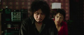 Movie still from “Oldboy” (2003), directed by Park Chan-wook – A man and a woman sitting next to each other in a room; Close Up shot, Over the shoulder angle