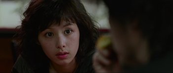 Movie still from “Oldboy” (2003), directed by Park Chan-wook – A young woman sitting in front of a man eating a piece of fruit; Close Up shot, Over the shoulder angle