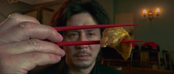 Movie still from “Oldboy” (2003), directed by Park Chan-wook – A man holding chopsticks with food in front of his face; Extreme Close Up shot, Overhead angle