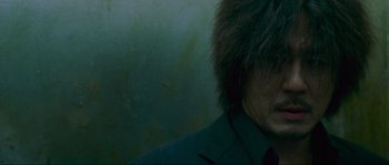 Movie still from “Oldboy” (2003), directed by Park Chan-wook – A man with a fur hat and a suit jacket on; Close Up shot, Low angle