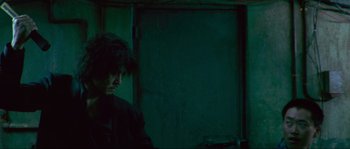 Movie still from “Oldboy” (2003), directed by Park Chan-wook – A man standing in a dark room next to a door; Medium shot, Low angle