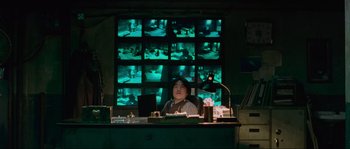 Movie still from “Oldboy” (2003), directed by Park Chan-wook – A woman sitting at a desk in front of a wall of monitors; Medium shot, Over the shoulder angle