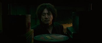 Movie still from “Oldboy” (2003), directed by Park Chan-wook – A man sitting in front of a plate of food; Close Up shot, Low angle