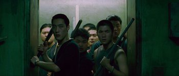 Movie still from “Oldboy” (2003), directed by Park Chan-wook – A group of young men standing next to each other holding guns; Medium shot, High angle