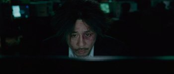 Movie still from “Oldboy” (2003), directed by Park Chan-wook – A man with black hair looking at a computer screen; Close Up shot, High angle