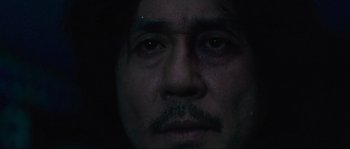 Movie still from “Oldboy” (2003), directed by Park Chan-wook – A person's face with a dark background; Extreme Close Up shot, Low angle