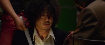 Movie still from “Oldboy” (2003), directed by Park Chan-wook – A person wearing a suit and tie; Close Up shot, Low angle