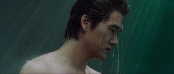 Movie still from “Oldboy” (2003), directed by Park Chan-wook – A young man with no shirt in the rain; Close Up shot, Overhead angle