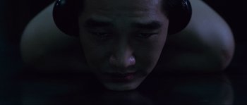 Movie still from “Oldboy” (2003), directed by Park Chan-wook – A young man is looking down at his face in the dark; Extreme Close Up shot, Overhead angle