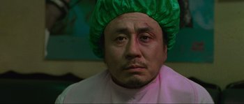 Movie still from “Oldboy” (2003), directed by Park Chan-wook – A person wearing a green hat; Close Up shot, Over the shoulder angle