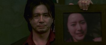 Movie still from “Oldboy” (2003), directed by Park Chan-wook – A man holding up a picture of a woman's face; Extreme Close Up shot, Over the shoulder angle