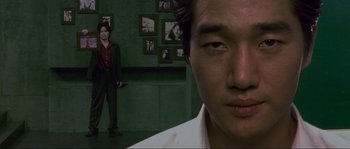 Movie still from “Oldboy” (2003), directed by Park Chan-wook – A man standing next to another man in front of a wall; Close Up shot, Over the shoulder angle
