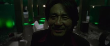 Movie still from “Oldboy” (2003), directed by Park Chan-wook – A man smiling for the camera in a dark room; Close Up shot, Low angle