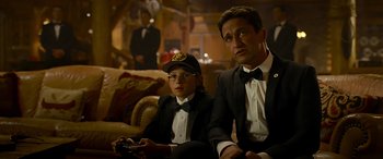 Movie still from “Olympus Has Fallen” (2013), directed by Antoine Fuqua – A man and a woman sitting next to each other holding remotes; Medium shot, Over the shoulder angle