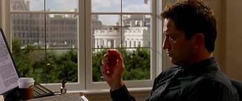 Movie still from “Olympus Has Fallen” (2013), directed by Antoine Fuqua – A man holding an apple in front of a window; Close Up shot, Over the shoulder angle