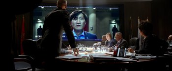 Movie still from “Olympus Has Fallen” (2013), directed by Antoine Fuqua – A man standing at a table in front of a large screen tv; Medium shot, Over the shoulder angle
