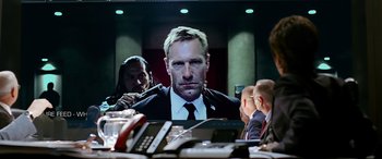 Movie still from “Olympus Has Fallen” (2013), directed by Antoine Fuqua – A man in a suit and tie sitting in front of other men; Close Up shot, Over the shoulder angle