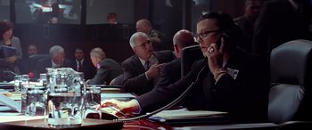 Movie still from “Olympus Has Fallen” (2013), directed by Antoine Fuqua – A woman talking on a phone in front of other men; Medium shot, Low angle