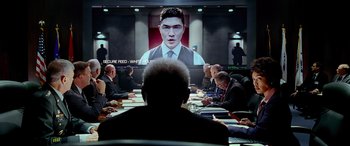 Movie still from “Olympus Has Fallen” (2013), directed by Antoine Fuqua – A group of people sitting at a table in front of a screen; Medium shot, Over the shoulder angle