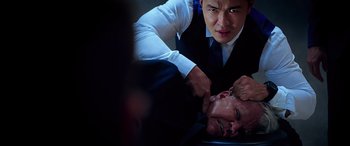 Movie still from “Olympus Has Fallen” (2013), directed by Antoine Fuqua – A man in a white shirt and a black tie is holding a man's head; Close Up shot, Over the shoulder angle