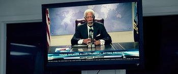 Movie still from “Olympus Has Fallen” (2013), directed by Antoine Fuqua – A man sitting at a desk in front of a television; Medium shot, High angle