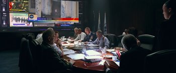 Movie still from “Olympus Has Fallen” (2013), directed by Antoine Fuqua – A group of people sitting around a table in front of a screen; Wide shot, Over the shoulder angle