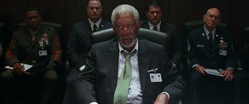 Movie still from “Olympus Has Fallen” (2013), directed by Antoine Fuqua – An older man in a suit and tie sitting in a chair; Medium shot, Low angle