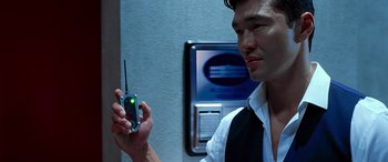 Movie still from “Olympus Has Fallen” (2013), directed by Antoine Fuqua – A man holding up a cell phone in front of another man; Close Up shot, Over the shoulder angle