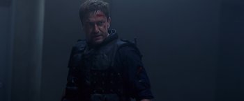 Movie still from “Olympus Has Fallen” (2013), directed by Antoine Fuqua – A man in a black jacket with a red bandage on his face; Medium shot, Low angle