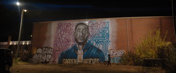 Movie still from “On the Come Up” (2022), directed by Sanaa Lathan – A man walking past a mural of a black man; Wide shot, Low angle