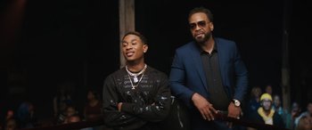 Movie still from “On the Come Up” (2022), directed by Sanaa Lathan – A man standing next to a man in a suit; Medium shot, Over the shoulder angle