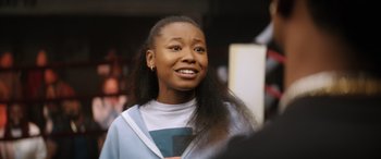 Movie still from “On the Come Up” (2022), directed by Sanaa Lathan – A young woman is smiling while holding a book in her hands; Close Up shot, Over the shoulder angle