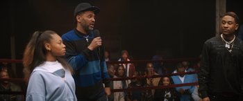 Movie still from “On the Come Up” (2022), directed by Sanaa Lathan – A man is speaking in front of an audience; Medium shot, Over the shoulder angle