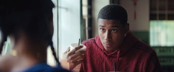Movie still from “On the Come Up” (2022), directed by Sanaa Lathan – A young man holding a cup of hot chocolate; Close Up shot, Over the shoulder angle