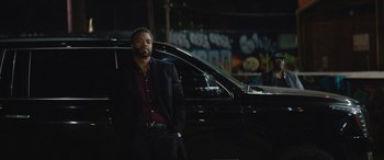 Movie still from “On the Come Up” (2022), directed by Sanaa Lathan – A man standing in front of a car at night; Medium shot, Over the shoulder angle